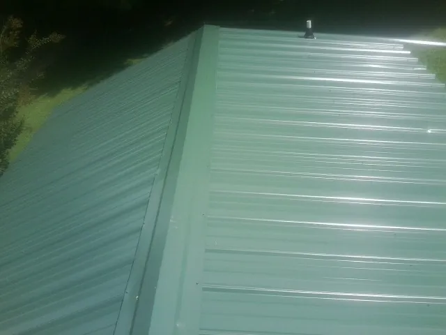 New green metal panels meeting at the ridge of a roof — Flat Roof Repair work by our crew in Honea Path
