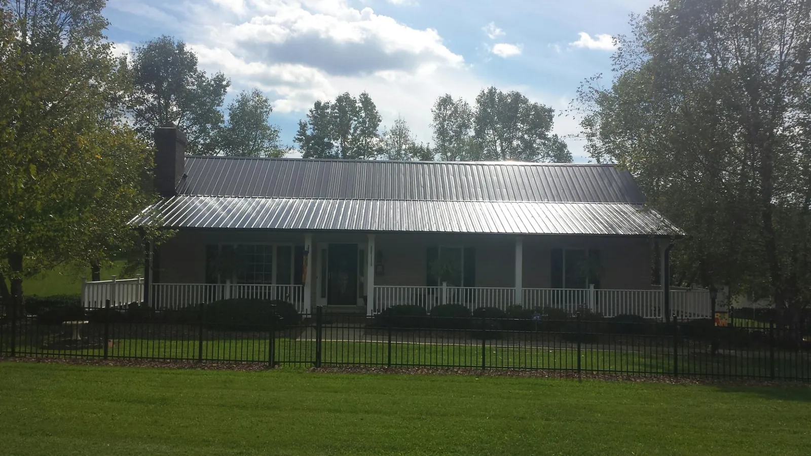 Gray metal roof on a brick ranch with a full width front porch — Gutter Guard Installation work by our crew in Honea Path