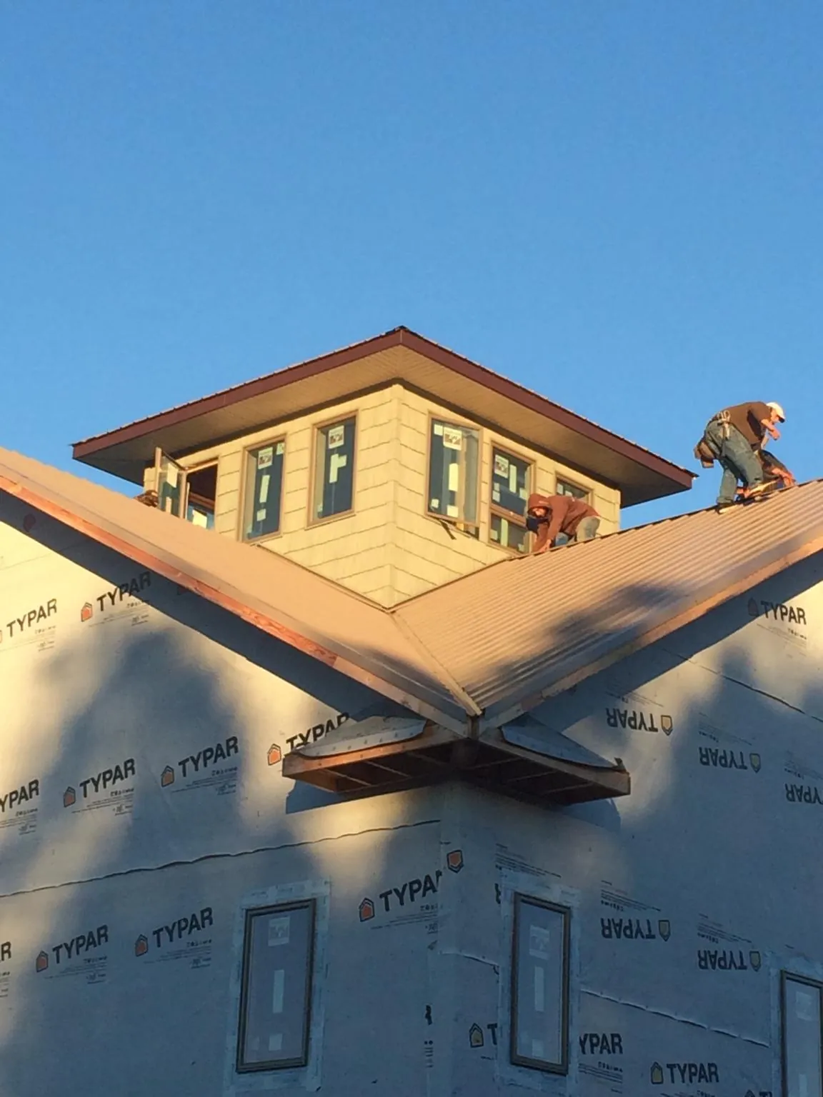 Roofers working around a rooftop cupola on a new metal roof at sunset — Roof Waterproofing in Honea Path by Roofing Brothers